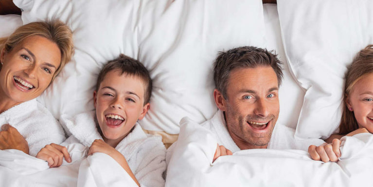 urlaub-mit-kindern-alpenpark- Familie kuschelt im Bett